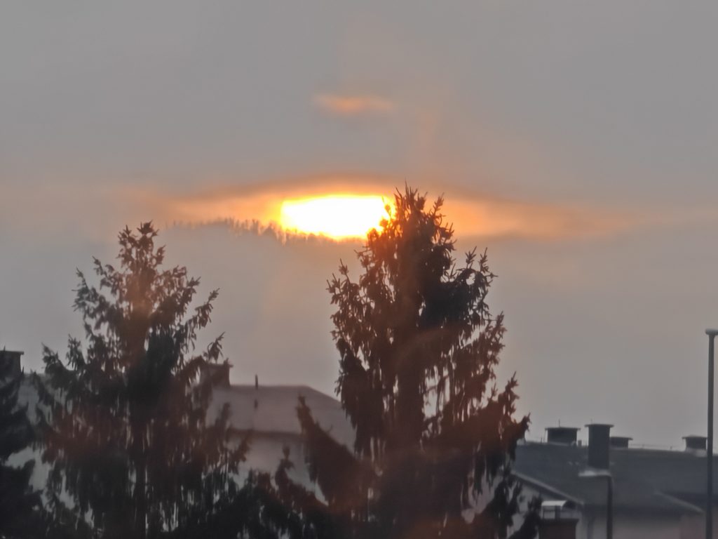 Europe Isn’t One Trip: How to Travel It Right, From the Balkans to Barcelona 1 Sunset over Celje, Slovenia with soft light breaking through clouds above rooftops and trees